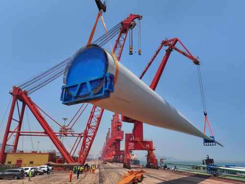 Wind turbine blade lifting with workers on site